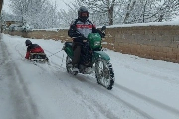 Motosiklete bağladığı kızaklarla çocukları karda eğlendirdi